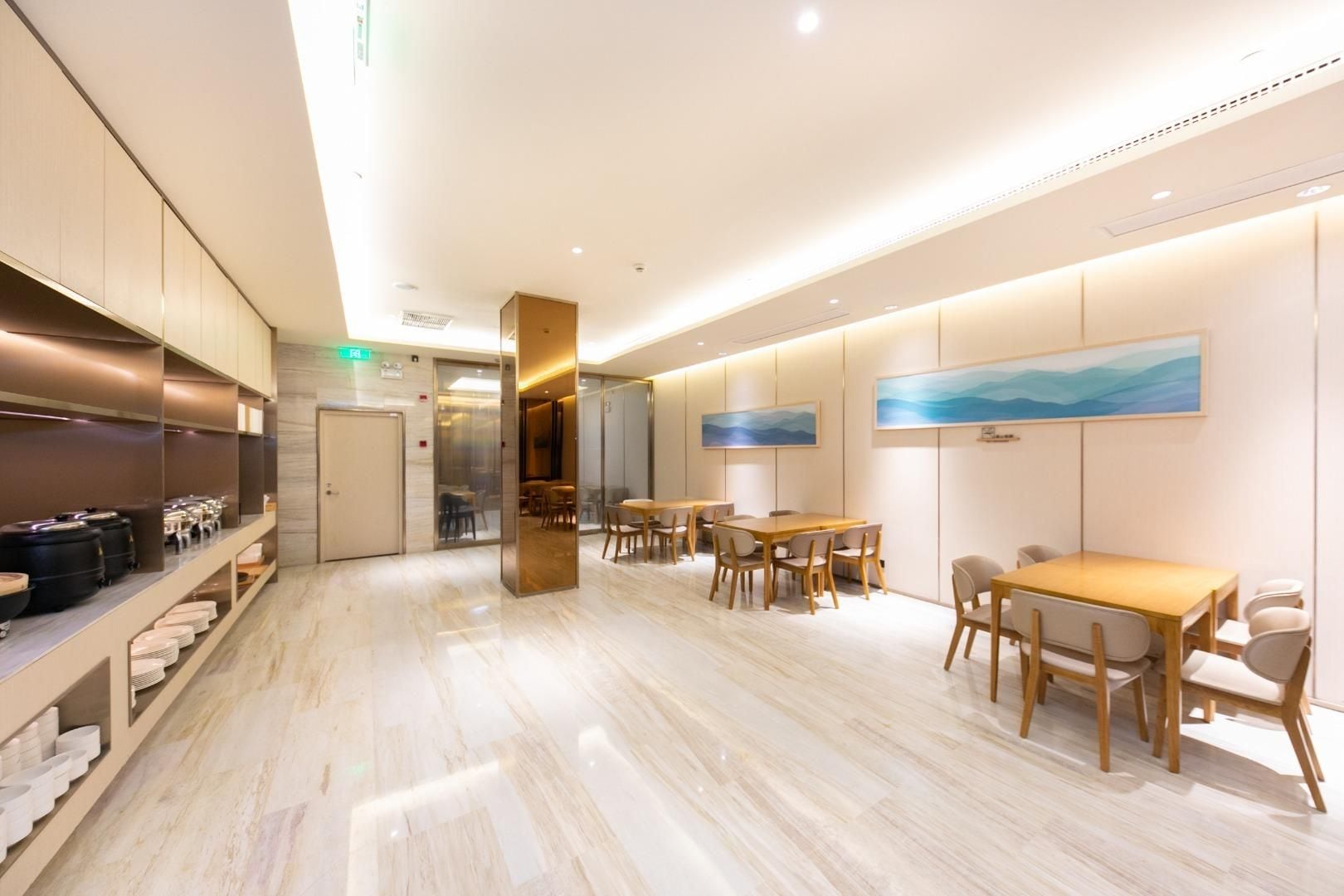 A hotel lobby with a marble floor, wooden tables and chairs, a coat rack, and a painting on the wall.