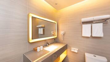 A modern bathroom with a large mirror, a sink, a toilet, and a towel rack.