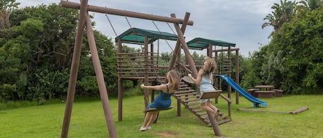 Un parque infantil con columpios y un tobogán.