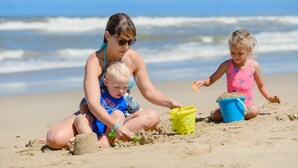 Three people sitting on a sandy beach with a blue bucket and a green shovel. - San Lameer Villa Rentals 3115 (Southbroom)