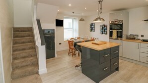 Una cucina moderna con isola centrale, forno integrato e zona pranzo con tavolo e sedie.