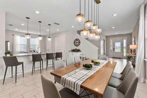 Una cocina moderna con una isla central, taburetes de bar e iluminación colgante.