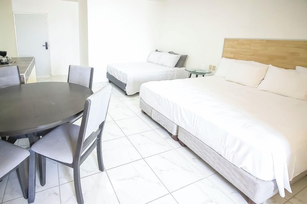 Une chambre d’hôtel avec deux lits, une table à manger et des chaises.