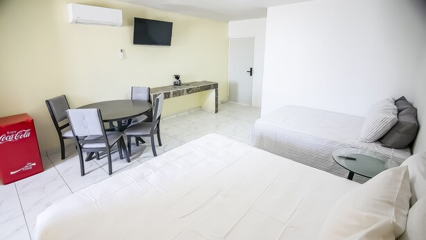 A hotel room with a bed, a desk, a chair, a small table, and a television. - OYO Hotel Plaza Las Torres, Cabo San Lucas (Cabo San Lucas)
