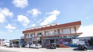 A multi-story building with various shops on the ground floor, including a bakery and a store with a sign that reads "alt." - OYO Hotel Plaza Las Torres, Cabo San Lucas (Cabo San Lucas)