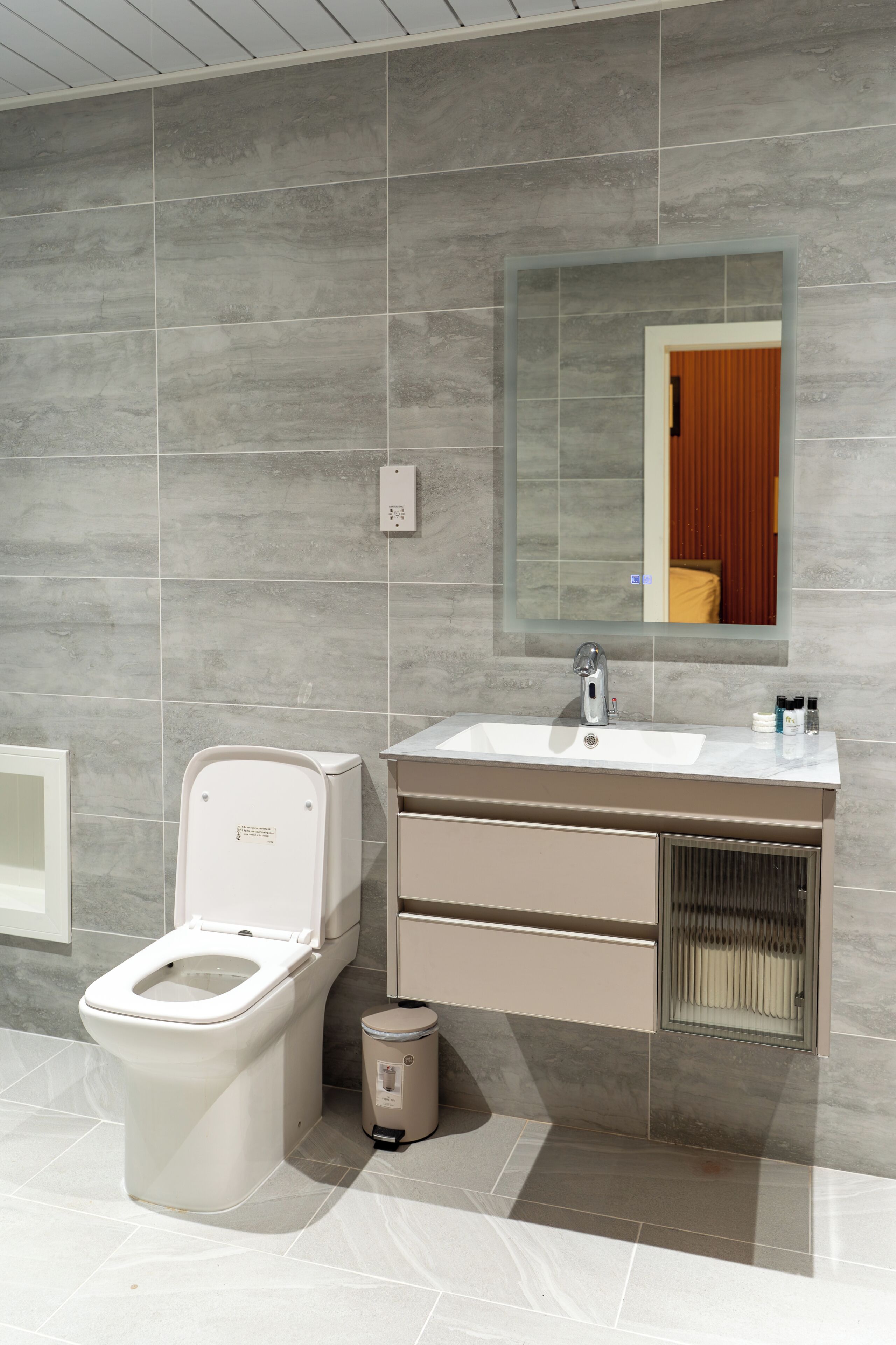 Un baño moderno con inodoro, lavamanos y espejo.
