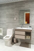 Un baño moderno con inodoro, lavamanos y espejo.