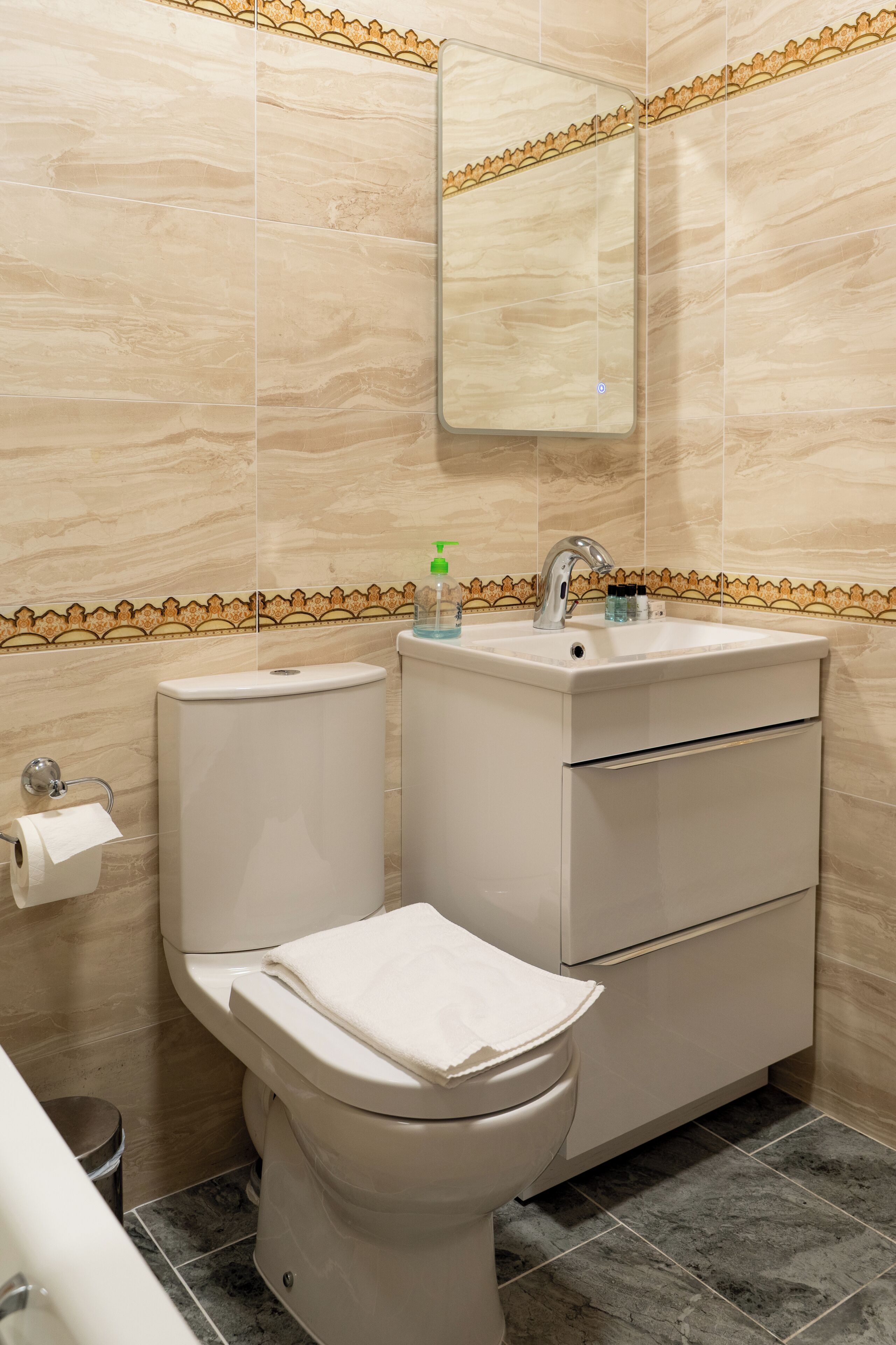 A bathroom with a toilet, sink, and mirror.