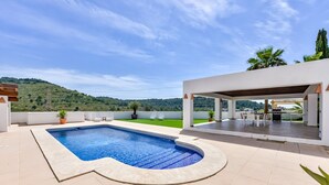 Une piscine offrant une vue sur un paysage verdoyant et des collines en arrière-plan.
