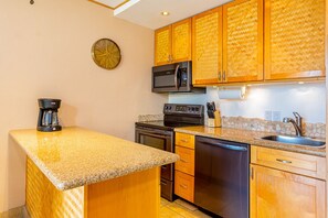 A compact kitchen with wooden cabinets, a microwave, a coffee maker, and a dishwasher.