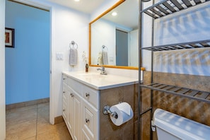 A bathroom with a white sink, a mirror, a towel rack, and a toilet.