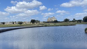 A calm lake with a reflection of the sky and clouds, surrounded by a golf course and a large hotel building in the background. - Golfer’s heaven, Orlando with 3 Champ courses (Kissimmee)