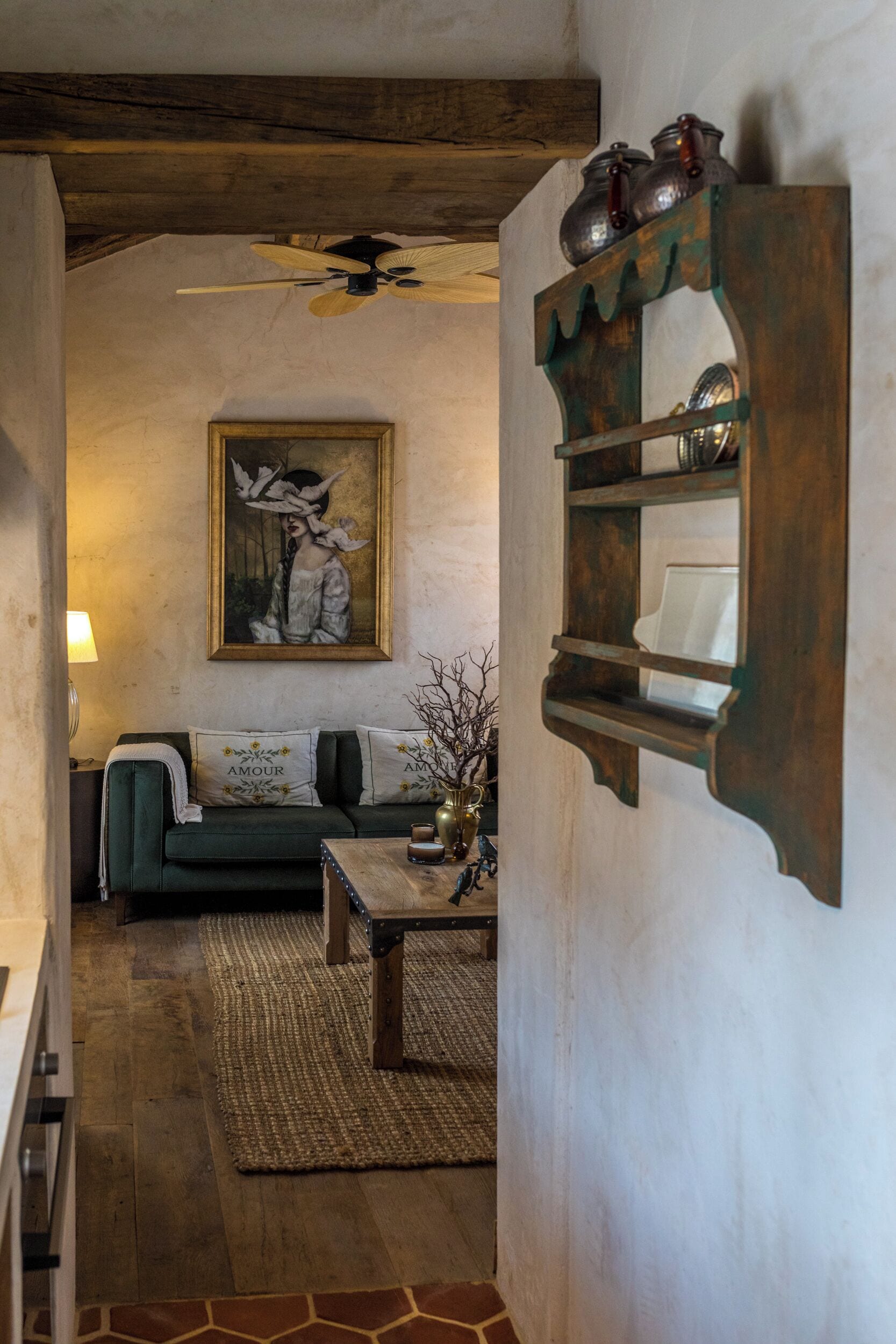 A cozy living room with a green sofa, a wooden coffee table, and a painting on the wall.