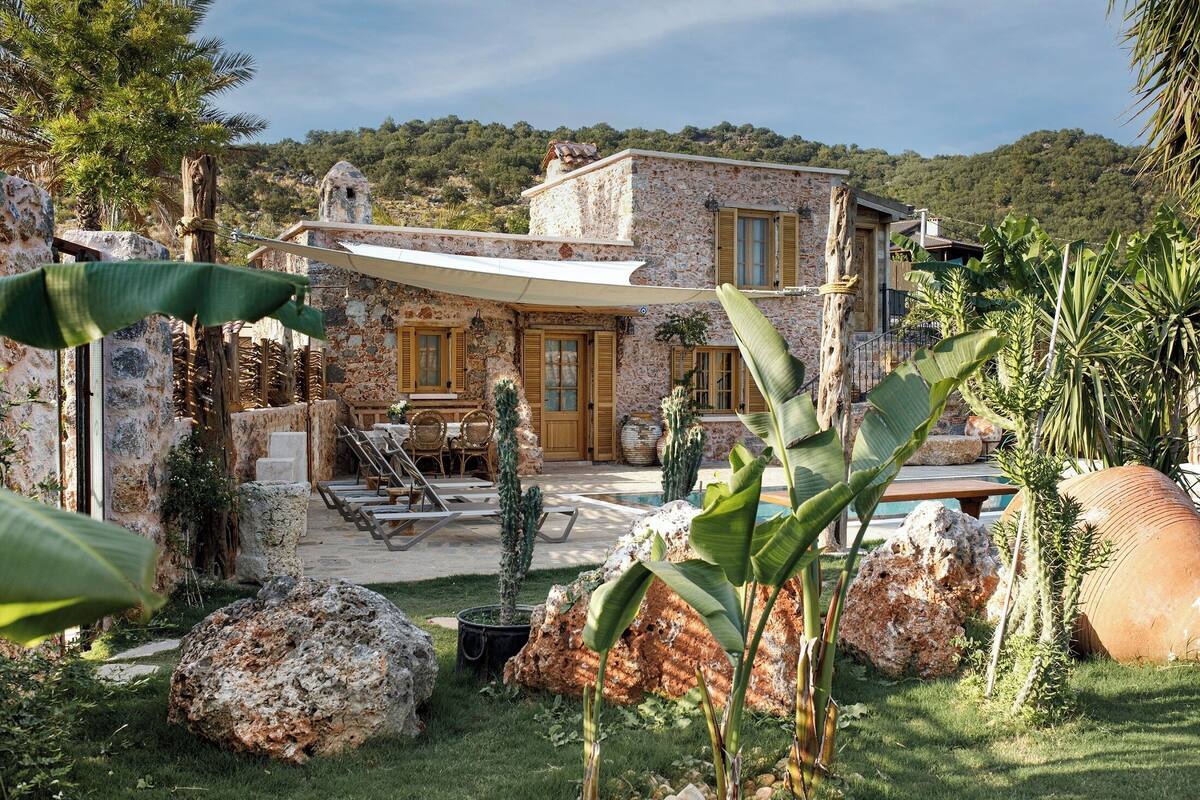 Une maison en pierre avec un patio, un espace salon extérieur et une piscine.