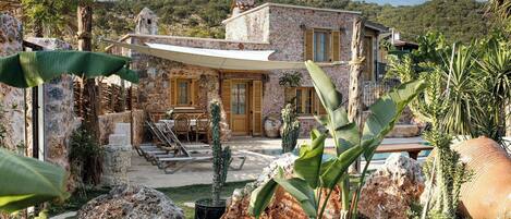 Una casa de piedra con un patio, mobiliario exterior y una piscina.
