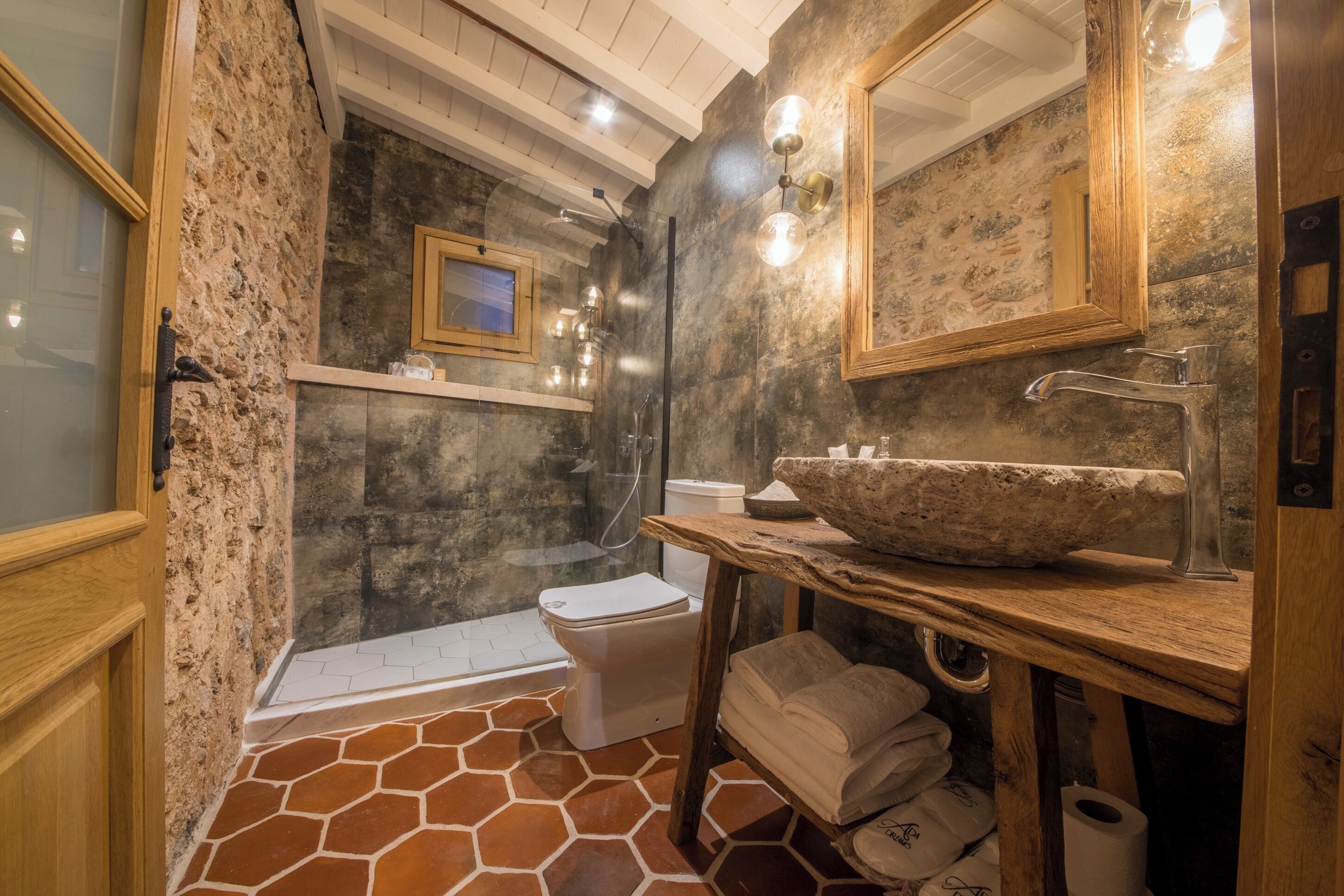 A bathroom with a stone sink, wooden vanity, and a shower area.