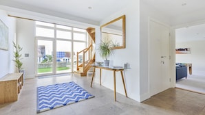 A spacious living area with a large window, a wooden staircase, a blue rug, and a potted plant. - All Views, Burton Bradstock, Bridport (Bridport)