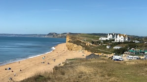 A coastal beach with a large white building, tents, and parked vehicles. - All Views, Burton Bradstock, Bridport (Bridport)