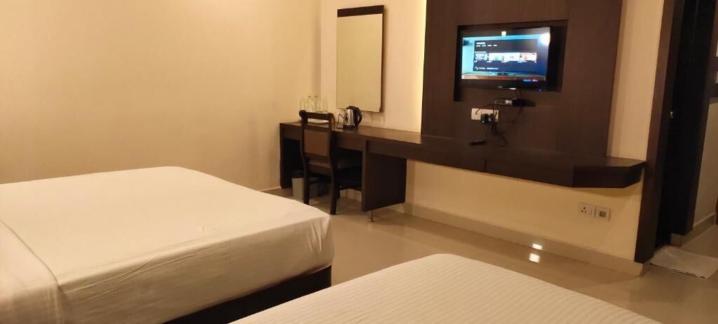 Ein Hotelzimmer mit Bett, Schreibtisch, Stuhl, einem an der Wand befestigten Fernseher und einem kleinen Tisch.