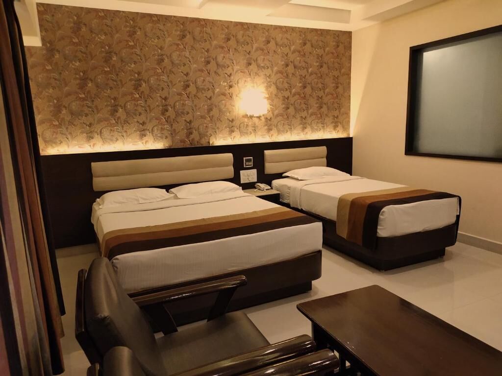 A hotel room with two beds, a desk, and a chair.