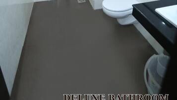 A bathroom with a toilet, a shower, and a sink.
