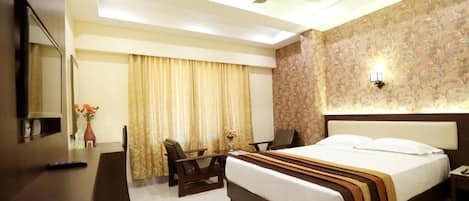 A hotel room with a bed, a desk, a chair, a ceiling fan, and a nightstand.