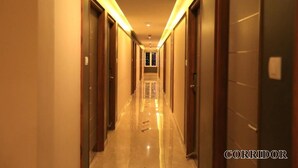 Un pasillo de hotel con puertas de madera a ambos lados, suelo brillante e iluminación empotrada en el techo.