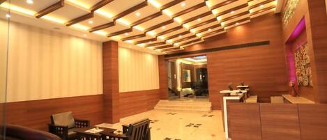 A lobby with wooden paneling, a reception desk, and a seating area with a sofa and chairs.