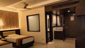 Habitación de hotel con cama, escritorio, espejo y baño con lavamanos y espejo.