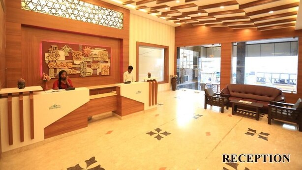 Un área de recepción con un mostrador de madera, una recepcionista y un sofá.