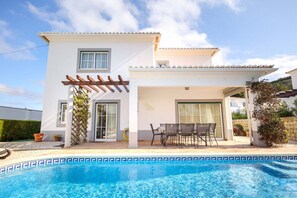 Une maison à deux étages dotée d’une piscine, d’une pergola et d’un patio aménagé avec du mobilier d’extérieur.