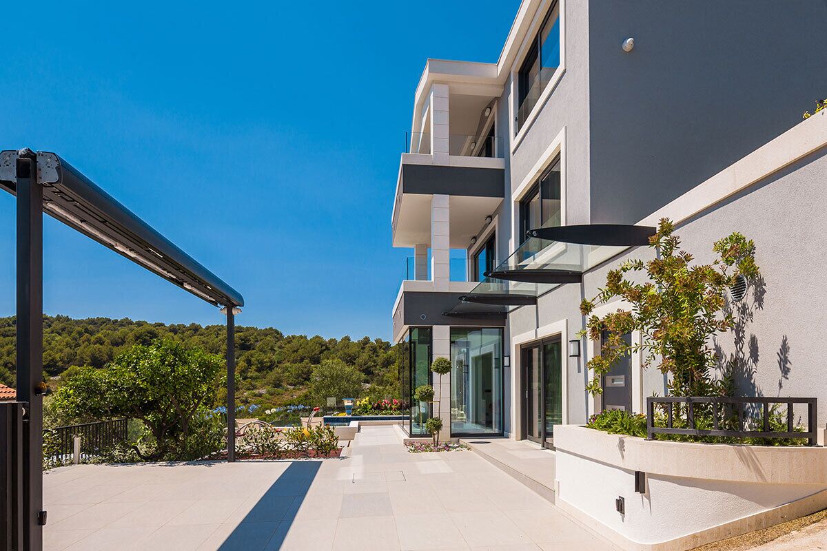 Un bâtiment moderne doté d’un espace extérieur couvert, de grandes fenêtres et offrant une vue sur un paysage verdoyant.