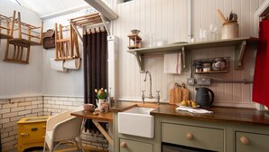 Una cocina compacta con un horno amarillo, una silla de madera y un lavabo.