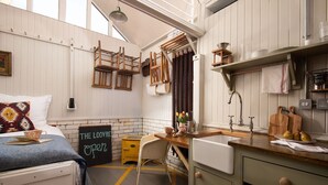 Una cocina compacta con muebles de madera, un comedor y una cama con vistas.