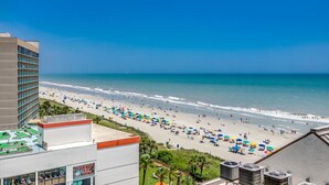 Vista a la playa desde un hotel con piscina y un cartel que dice 'Curry's Cafe'.