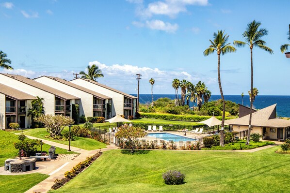 A resort with multiple buildings, a swimming pool, and palm trees.