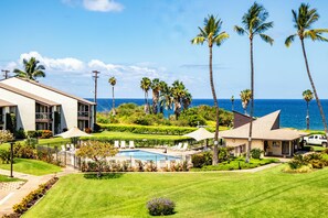A hotel with a pool, palm trees, and a view of the ocean.