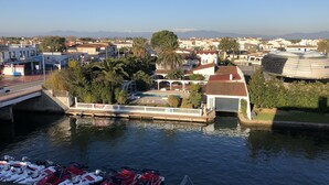 A marina with boats docked, a bridge, and buildings in the background.