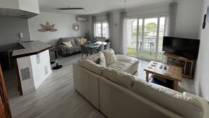 A modern living room with a sofa, a dining table, and a TV.