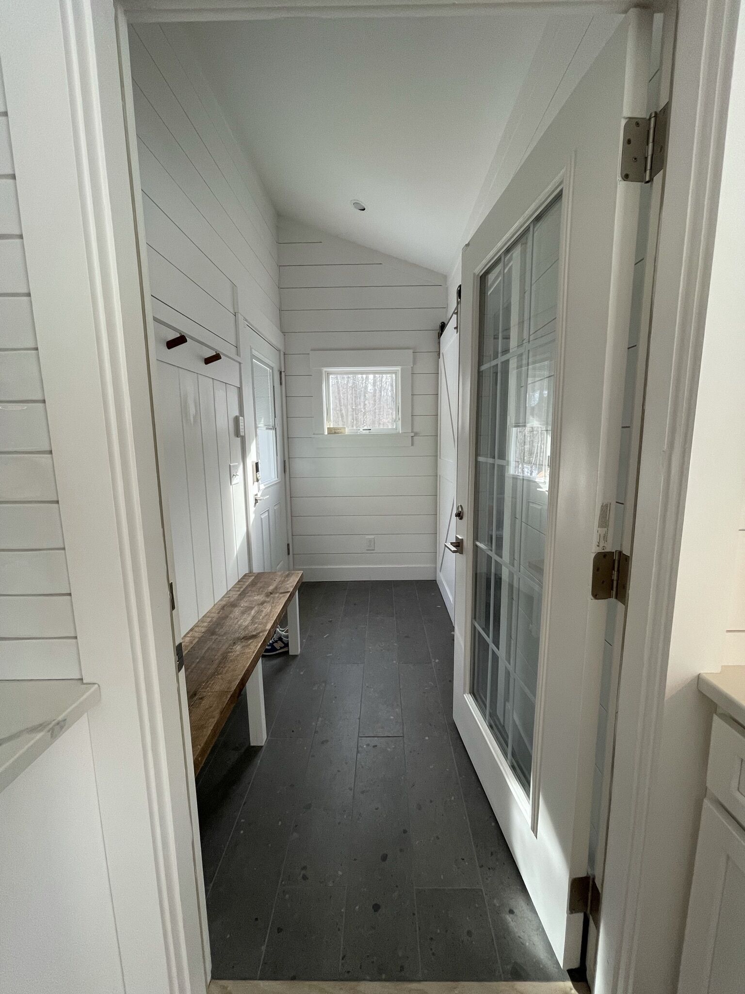 A narrow hallway with white walls and a bench.