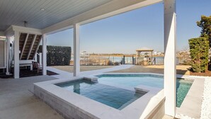 A covered outdoor swimming pool area with a view of a distant cityscape. - Sound front home w boat slip! New for 2026 pool! (Wrightsville Beach)