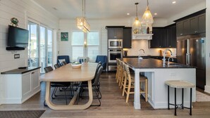 A modern kitchen with a central island, built-in appliances, and pendant lighting. - Sound front home w boat slip! New for 2026 pool! (Wrightsville Beach)