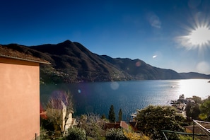 A lake with mountains in the background, a clear sky, and a building in the foreground.