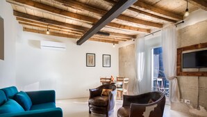 Una sala de estar con un sofá color turquesa, un sillón de cuero y un techo de madera.