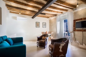 A living room with a teal sofa, a leather armchair, and a wooden ceiling.
