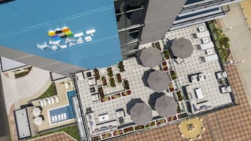 An aerial view of a hotel with a pool, outdoor seating, and a blue awning with a logo.
