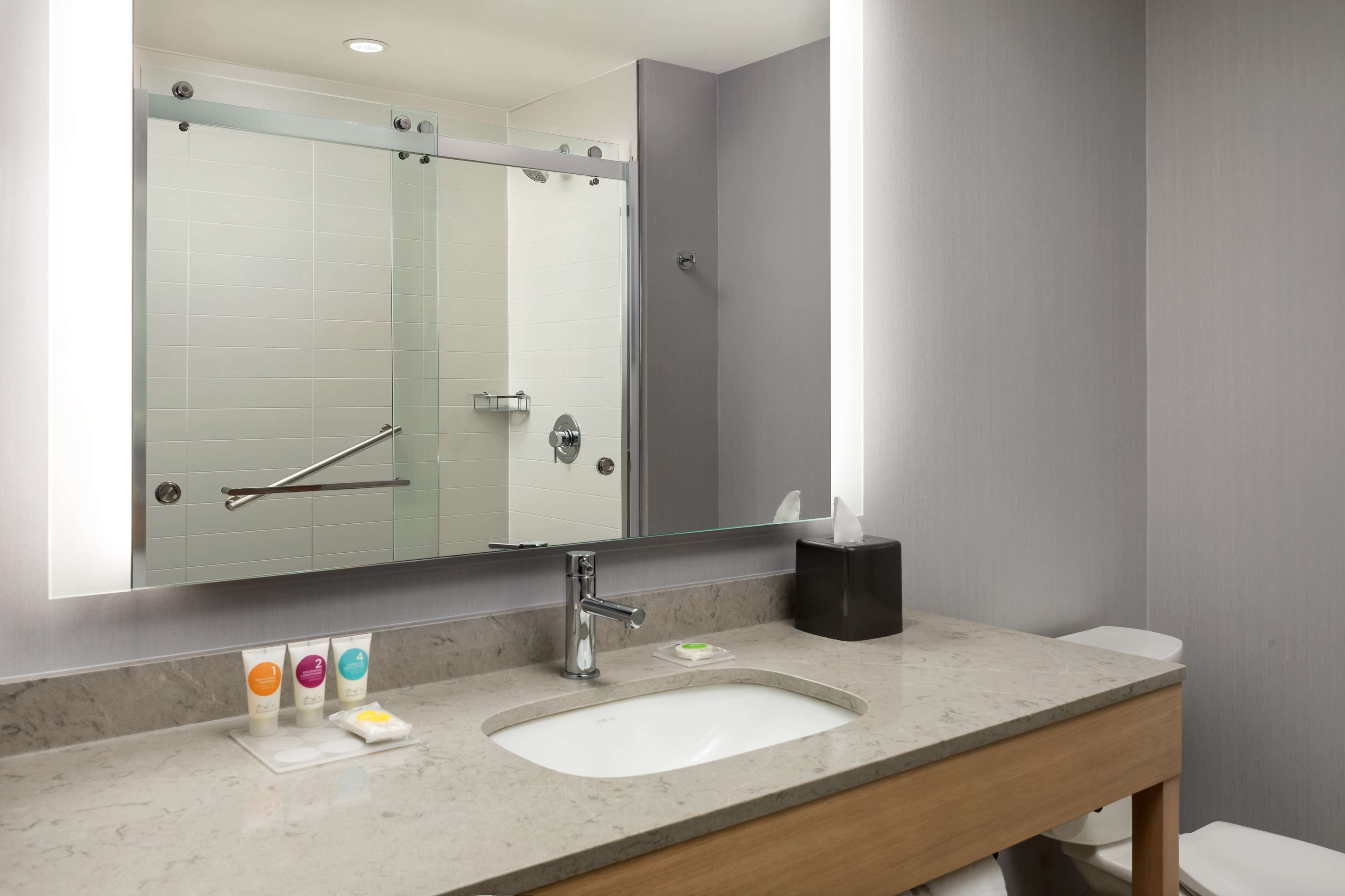 A modern bathroom with a large mirror, a sink, and a toilet.