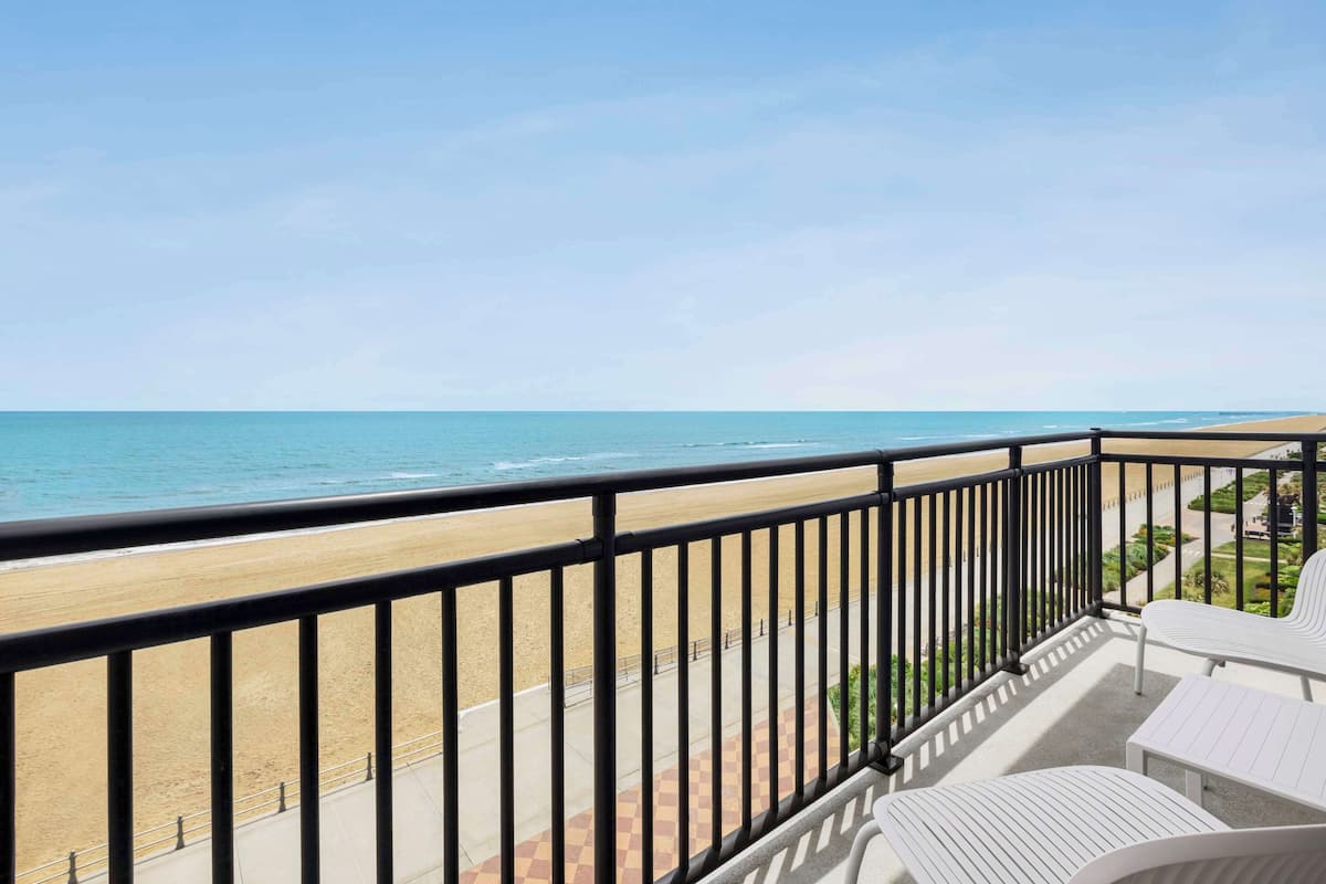 A balcony with a view of the beach and ocean.