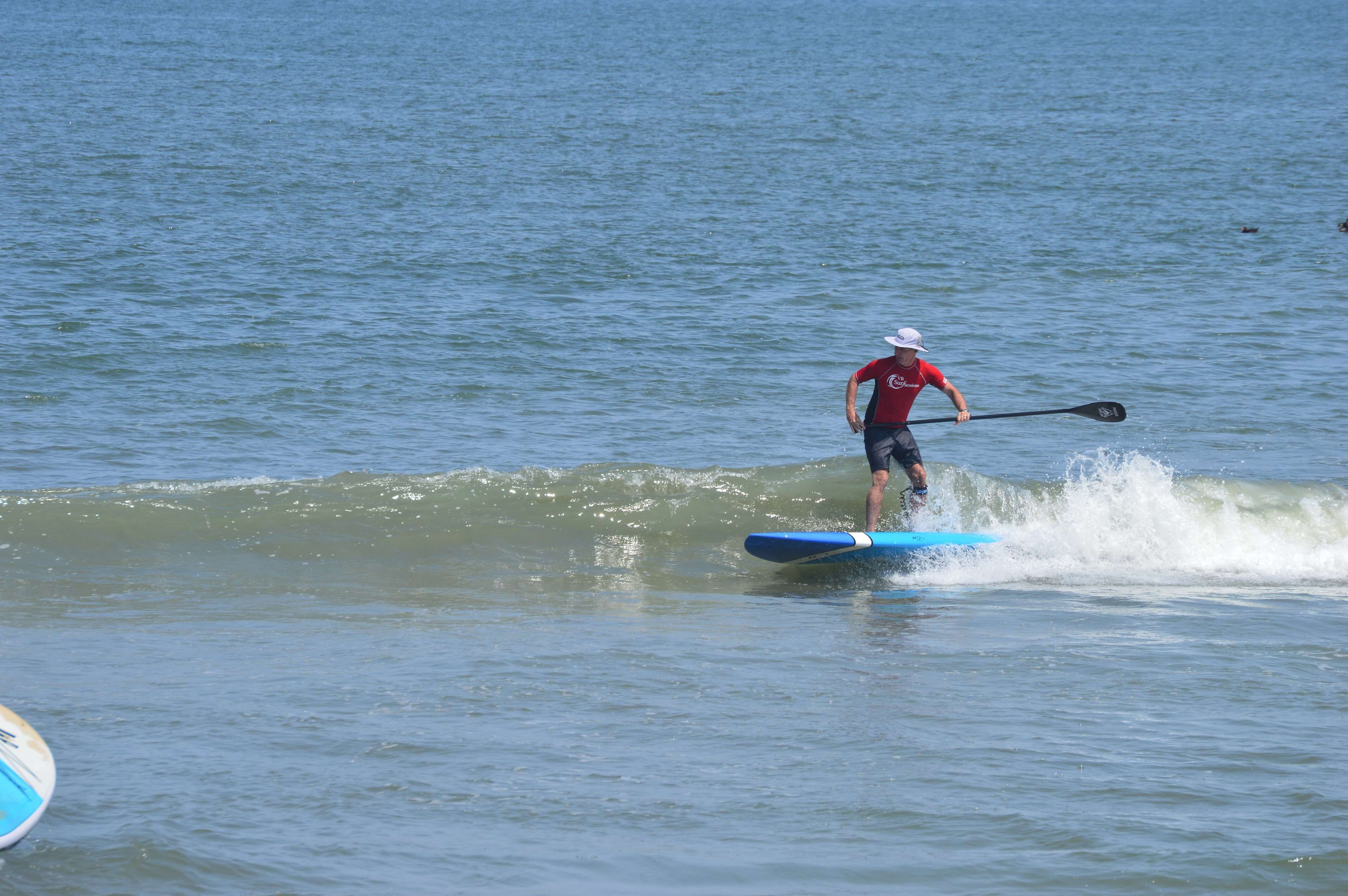 A person paddleboarding on a calm body of water.