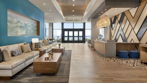 A spacious lobby with a large sofa, a coffee table, and a wall-mounted painting. - Hyatt Place Virginia Beach / Oceanfront (Virginia Beach)